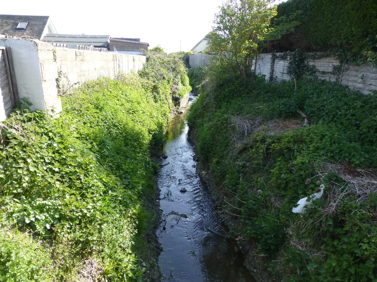 A stream running in a channel between houses on Charlmead, East Wittering