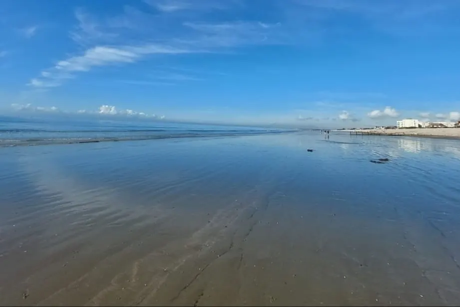 East Wittering beach at low tide, wet sand reflecting the sky, looking west towards Portsmouth