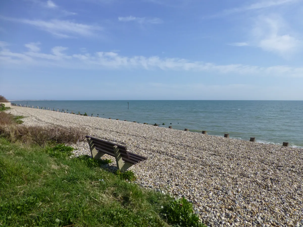 A bench on the shingle of East Wittering beach, looking out to sea